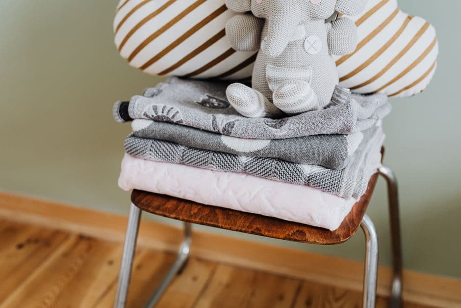 Linge de bébé plié sur une chaise, une peluche posée dessus